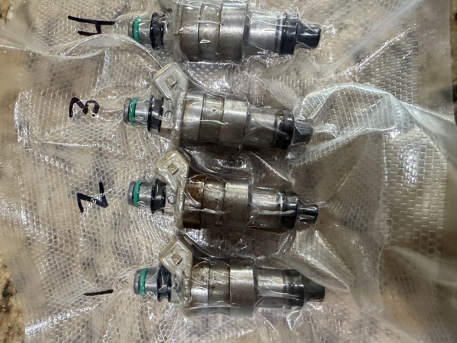 The same automotive injector set, cleaned and resealed with new o-rings, numbered and flow tested