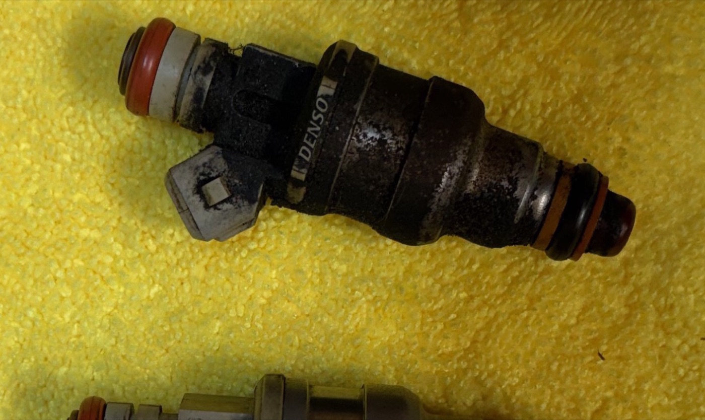 A marine fuel injector before cleaning — caked in carbon and varnish